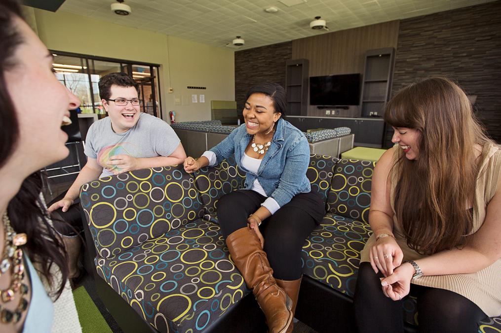 Four Keuka College students sit and laugh in their residence hall lounge.