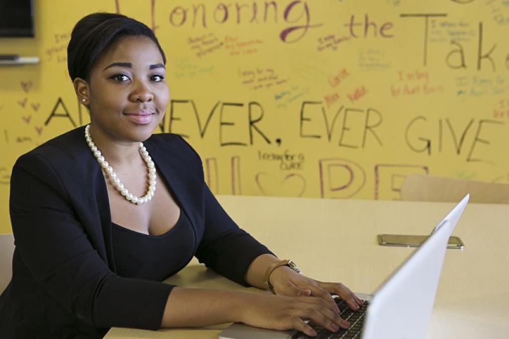 Student typing on a lap top looking at the camera