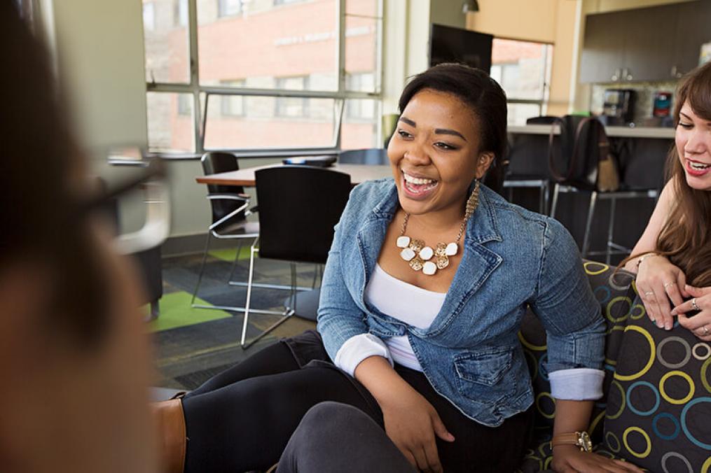 Young woman sitting in a classroom talking to people in front of her.