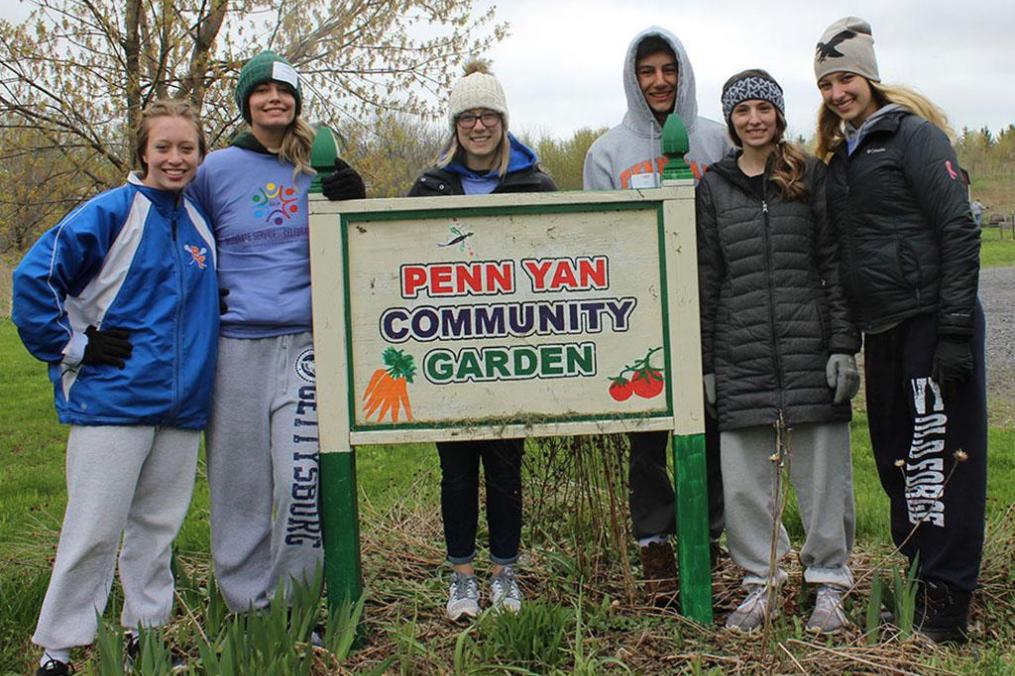 A group of students gathered around a sign that says "Penn Yan Community Garden"