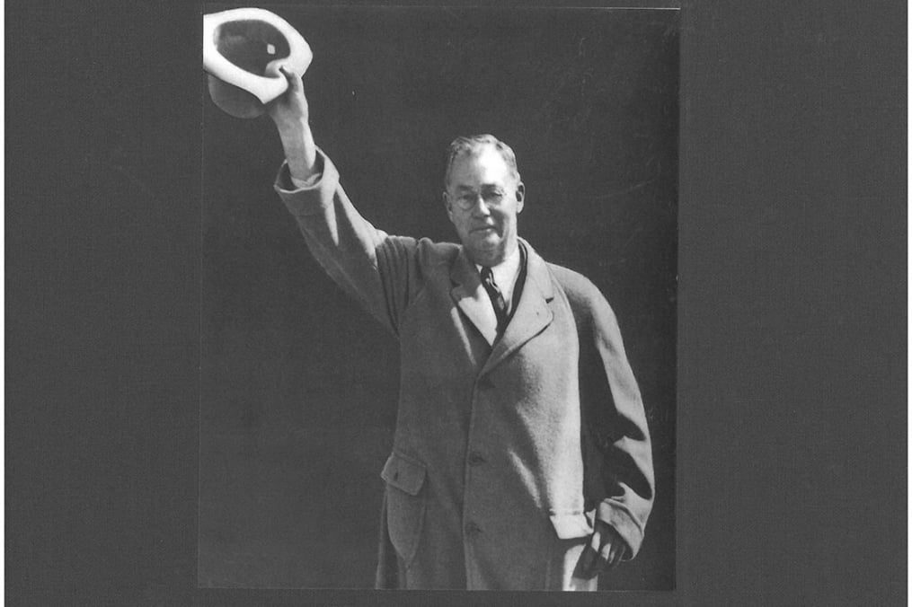 Black and white photo of Fred waving with his hat