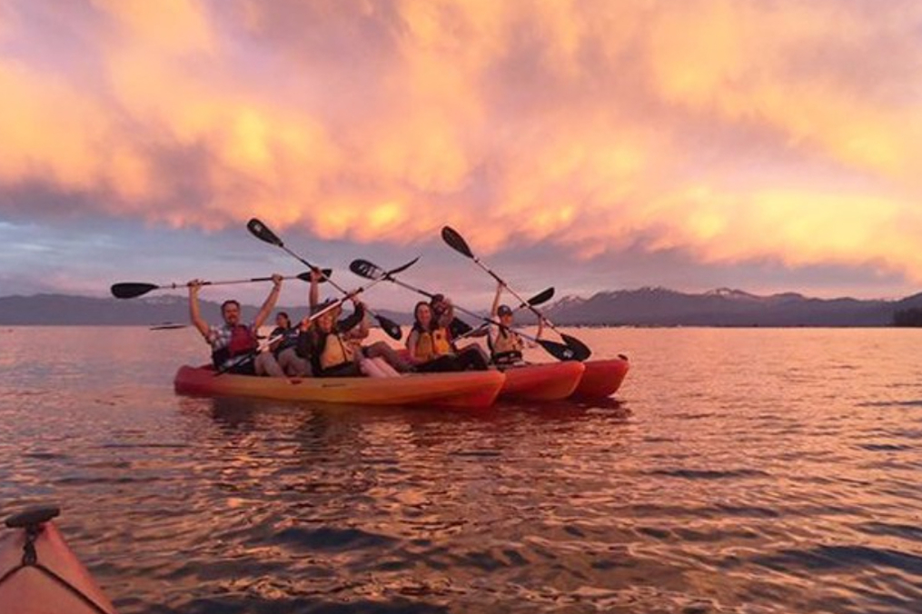 Three boats with students holding paddles up posing for a photo
