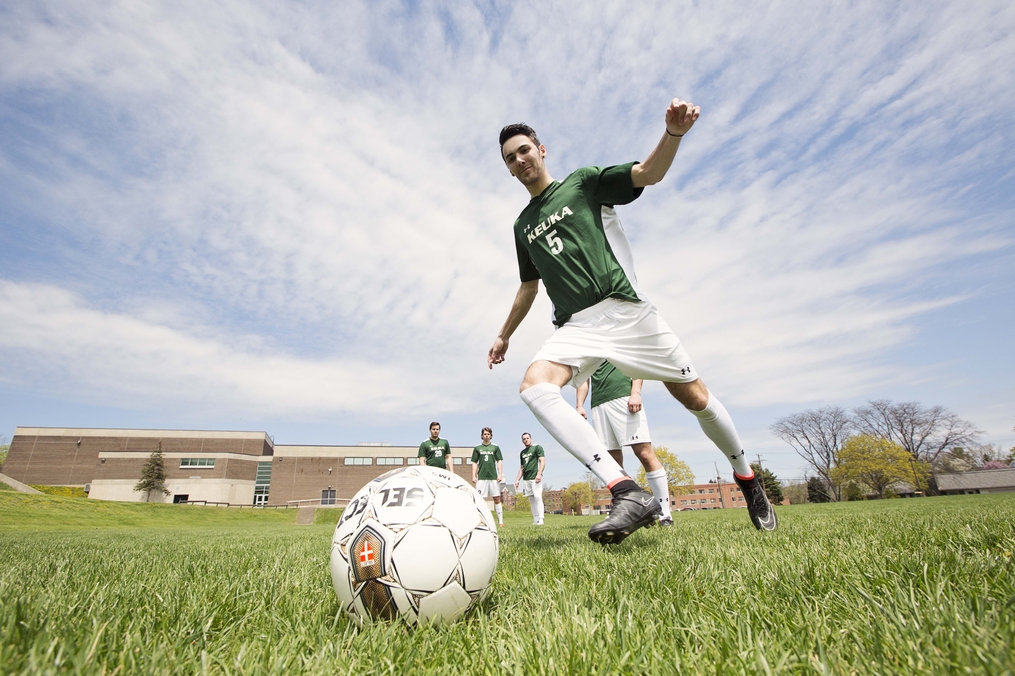 Student kicking a soccer ball outside of RAC Athletics Center 