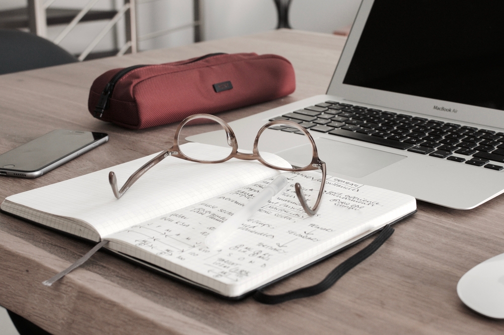 Open notebook with reading glasses and computer on a table