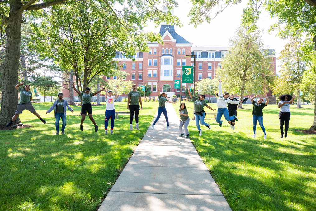 Students jump and pose on sidewalk leading to Ball Hall from Norton Chapel 