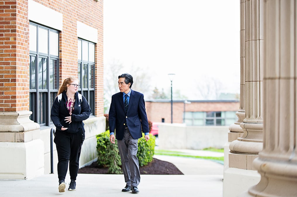 Dr. Leon walks with student in front of Hegeman Hall 