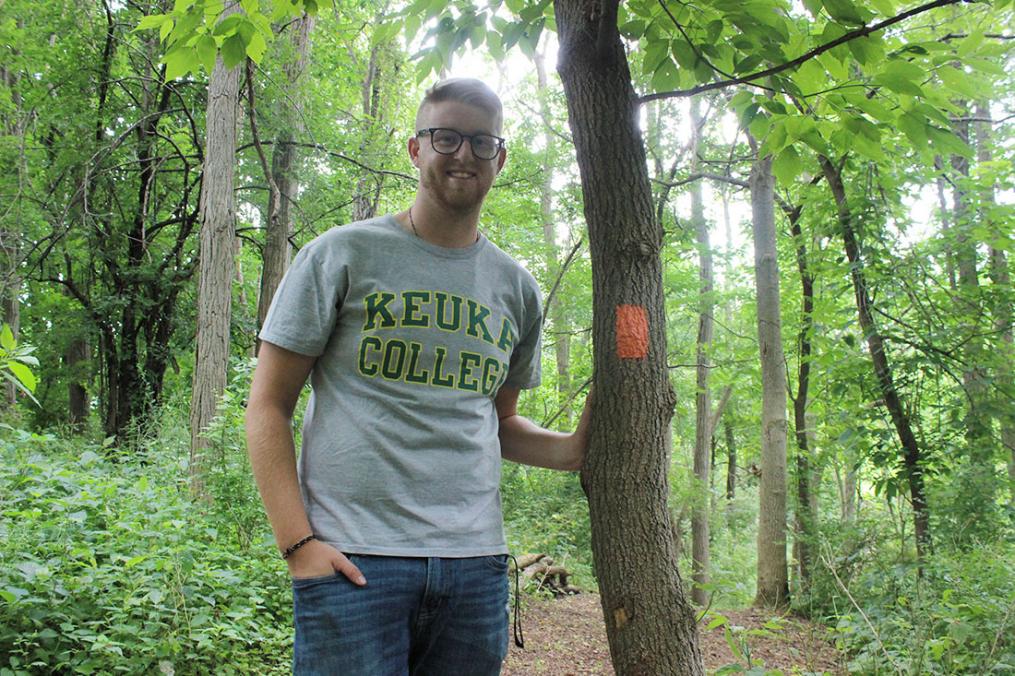 Senior Dan Lazzaro stands next to a sign marking a walking trail behind the Yates County Community Center in Penn Yan. The environmental science major used a Field Period® opportunity to create a cross-country trail for the Penn Yan Academy cross-country team.
