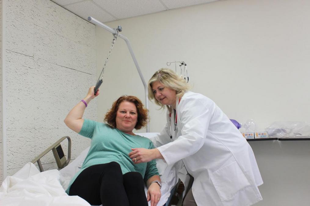Dr. Elizabeth Russo '98, chair of the Division of Nursing (r), demonstrates how to use a hospital bed trapeze with Dr. Susan Bezek, assistant professor of Nursing, in the College's new nursing lab.