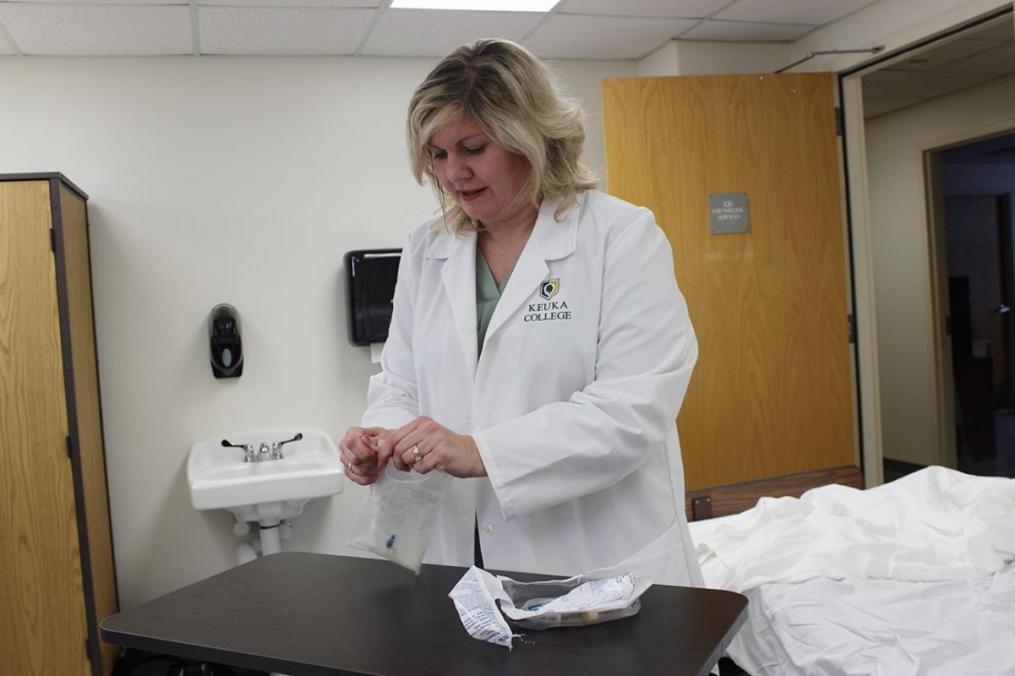 Dr. Elizabeth Russo '98, chair of the Division of Nursing, open a saline pack in the College's new nursing lab.