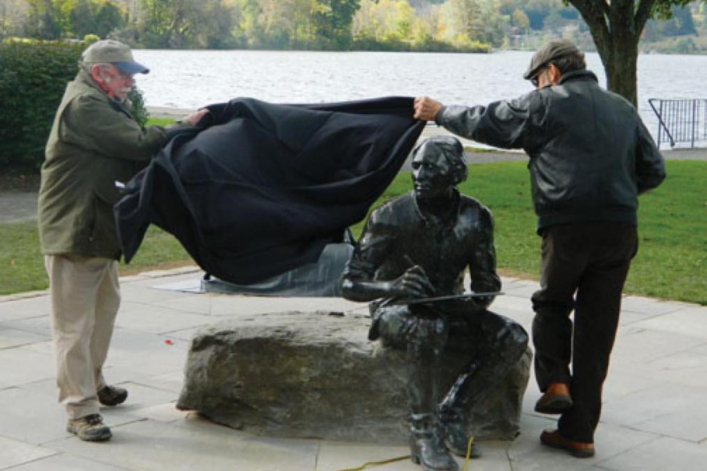 Paul Brooks (l), chair of the Lincklaen Statue Committee, and Dexter Benedict unveil the statue of the City of Cazenovia founder John Lincklaen. The statue was the first commissioned piece completed by Dexter after the fire at Fire Works Foundry.