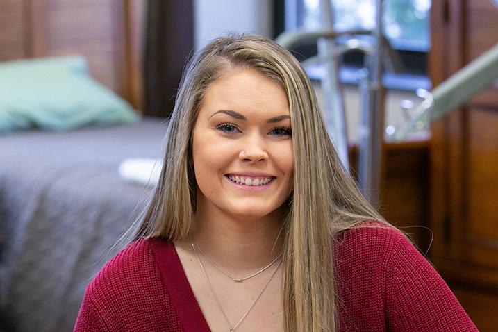 Kendall Neuberger sits in an OT lab with a number of OT tools behind her.
