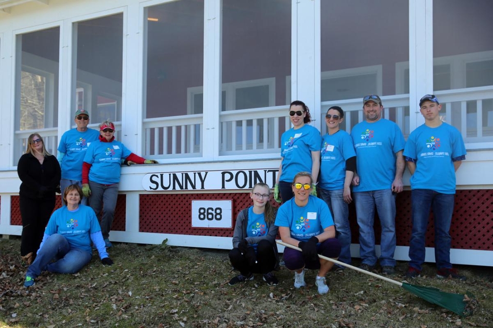 students posing outside of Sunny Point with lawn tools