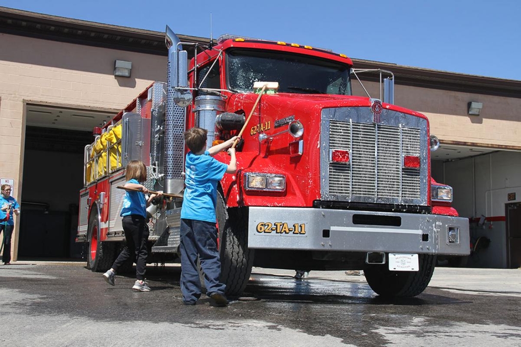 young boy helping wash a fire truck