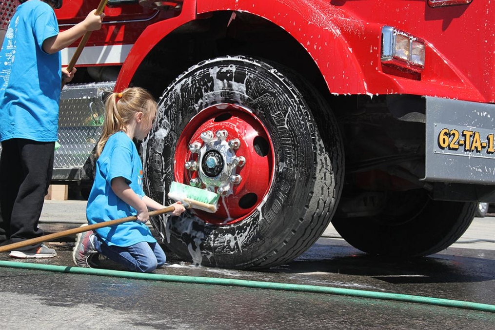 young girl helping wash a fire truck tire
