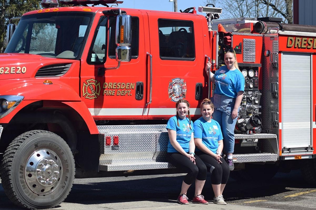 students posing on a fire truck after washing it