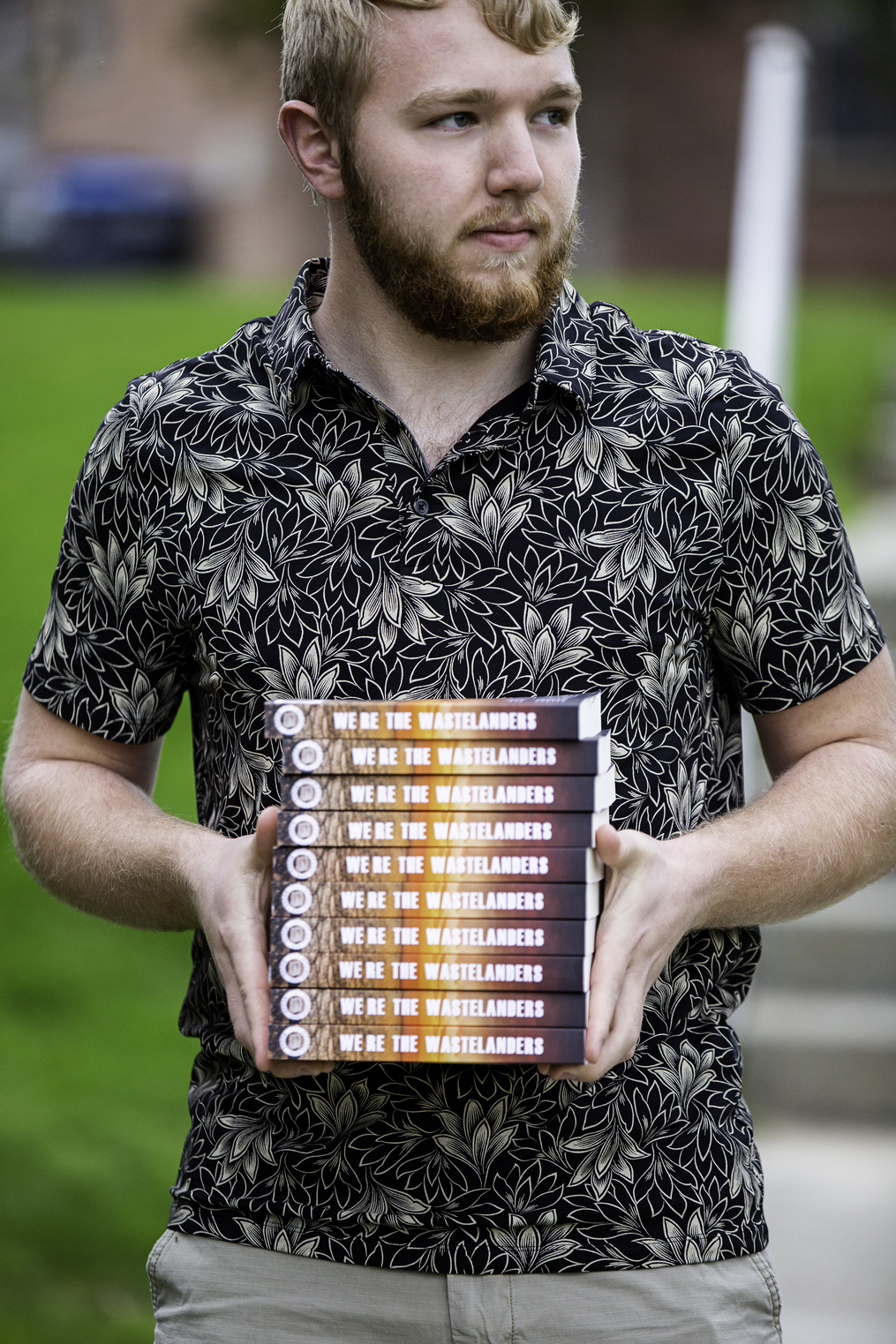 Lucas Nichols holding a stack of his recently published book 