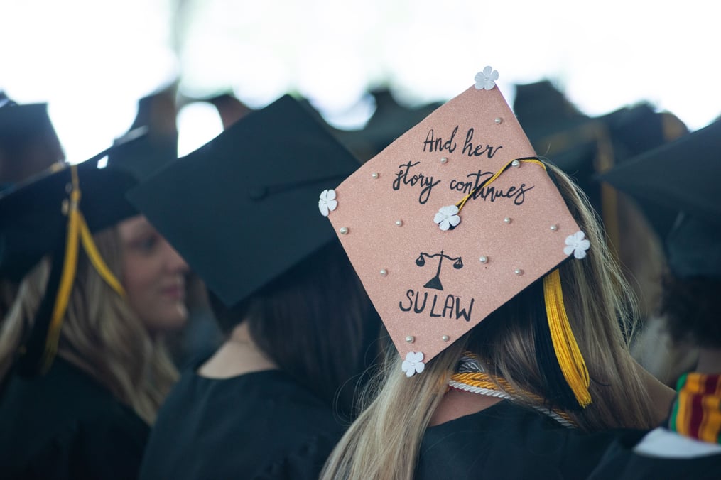 Amber Benjamin's Graduation Cap reads "And Her Story Continues - SU Law"