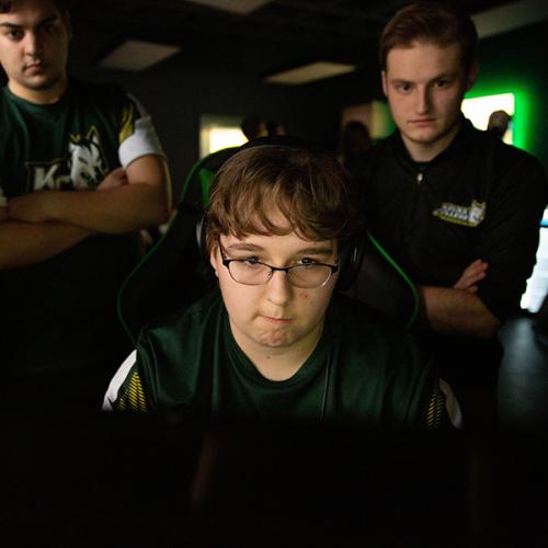 Three students gather around a computer in the Keuka College esports lab.