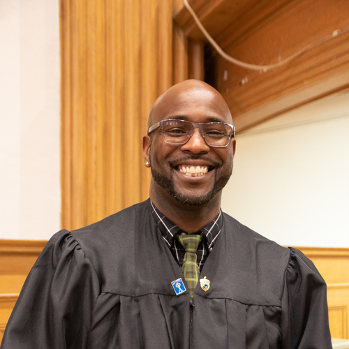 Portrait of Smith in his graduation gown posing in the chapel