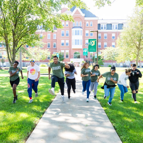 Students running toward the camera and away from Ball Hall 